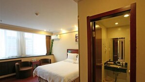 A hotel room with a bed, a chair, a desk, a window, and a bathroom with a sink and mirror. - Greentree Inn Qinghuangdao Sun City Hotel (Qinhuangdao)