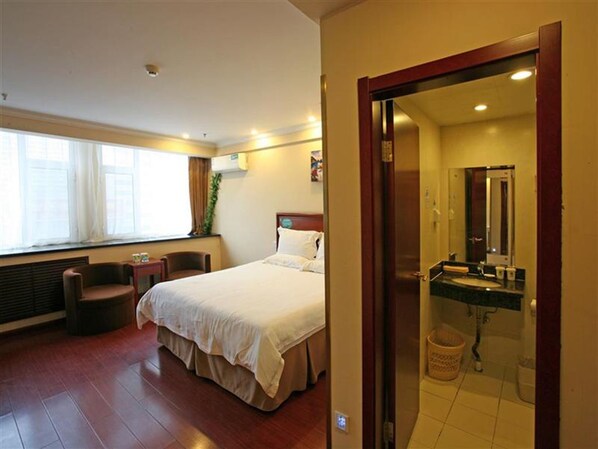 A hotel room with a bed, a chair, a desk, a window, and a bathroom with a sink and mirror. - Greentree Inn Qinghuangdao Sun City Hotel (Qinhuangdao)