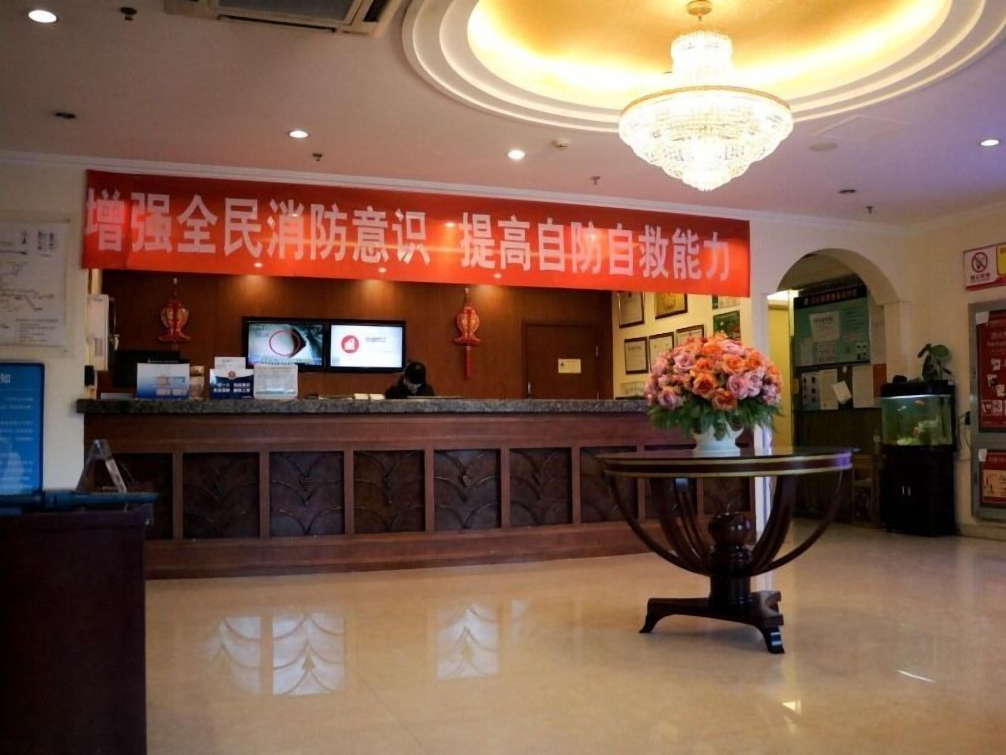 A reception desk with a red banner, a chandelier, and a flower arrangement.