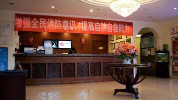 A reception desk with a red banner, a chandelier, and a flower arrangement.
