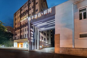 A hotel entrance with illuminated signage, a modern building facade, and a clear night sky.