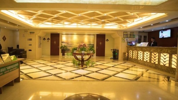A hotel lobby with a reception desk, a large decorative vase with flowers, a tiled floor, and a ceiling with a geometric pattern. - Greentree Inn Suzhou Station Hotel (Suzhou)