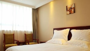 A hotel room with a large bed, two chairs, a small table, and a painting on the wall. - Greentree Inn Suzhou Station Hotel (Suzhou)