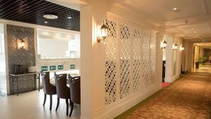 A hotel corridor with a dining area featuring a stone wall and modern chairs. - Greentree Inn Suzhou Station Hotel (Suzhou)