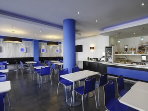 Un restaurant moderne au décor bleu et blanc, doté de plusieurs espaces de restauration et d’un comptoir de boissons en libre-service.