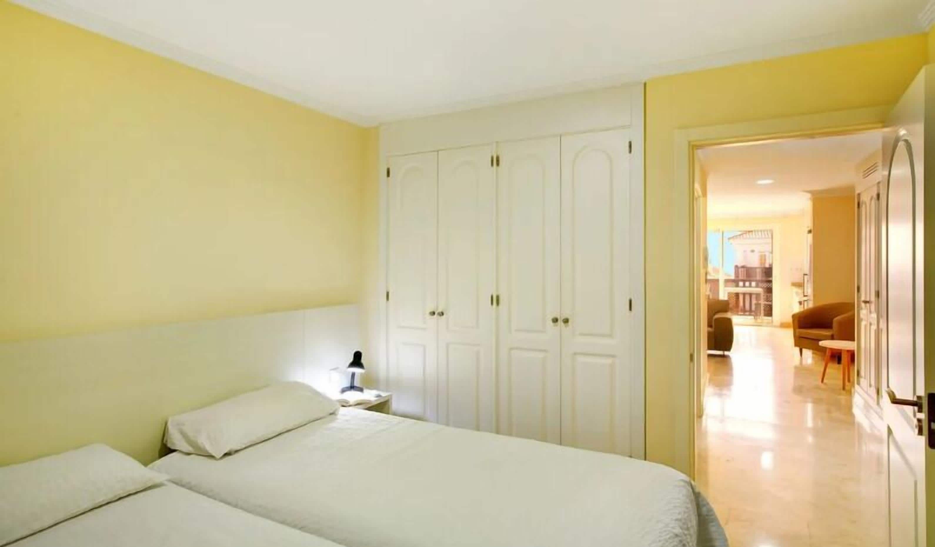 Un dormitorio con dos camas, un armario y vistas al salón.