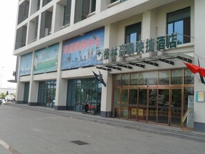 A hotel with a large glass facade, a signboard advertising a golf center, and a motorcycle parked outside. - GreenTree Inn Tianjin Wuqing Jingbin Industrial Park Chengwang Road Express Hotel (Tianjin)