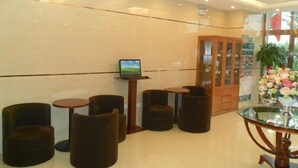 A lobby with a glass-top table, several round stools, a laptop on a small table, and a wooden cabinet with glass doors. - GreenTree Inn Tianjin Wuqing Jingbin Industrial Park Chengwang Road Express Hotel (Tianjin)