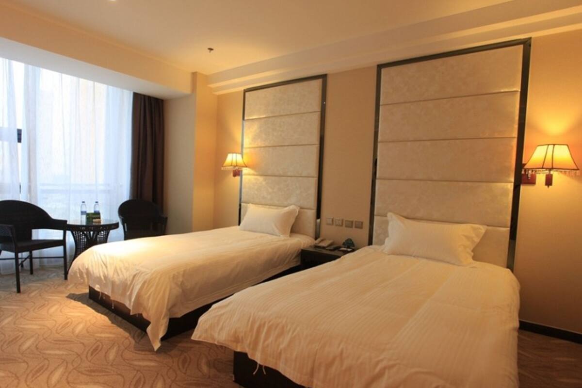 Habitación de hotel con dos camas, un escritorio y una silla.