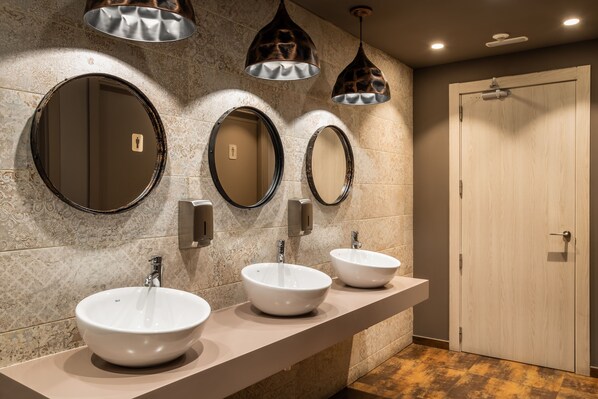 A bathroom with three round mirrors, a beige countertop, and a wooden door.