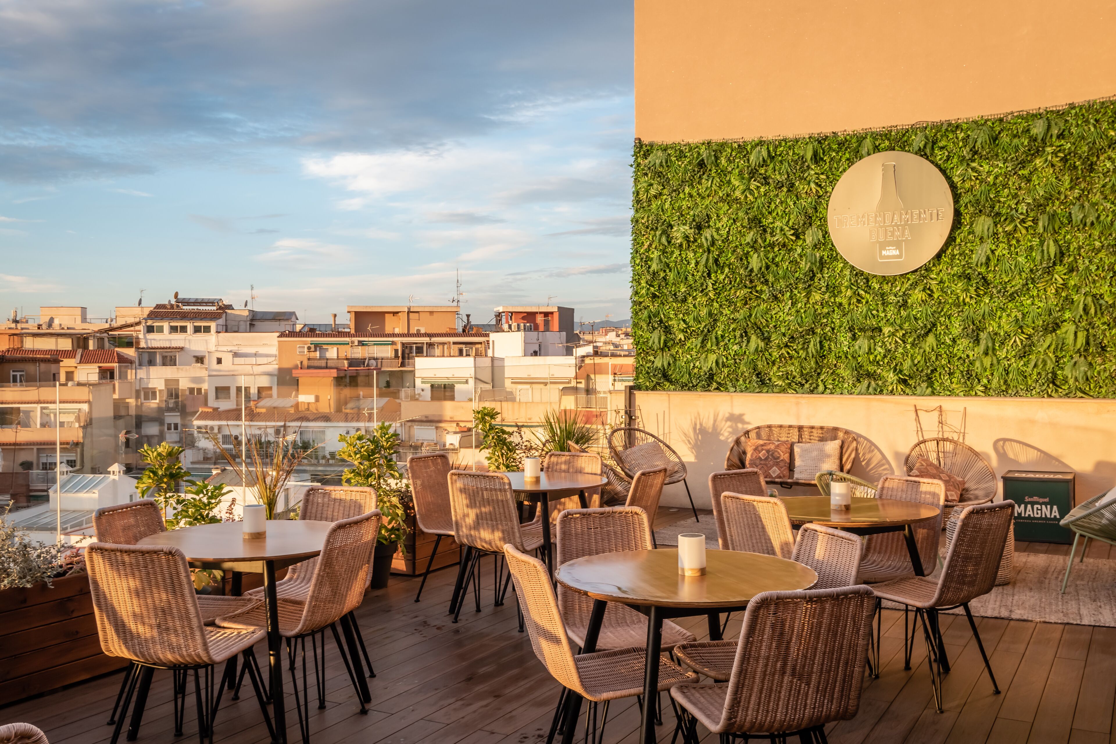 Terraza en la azotea con mobiliario de mimbre y vistas a la ciudad.