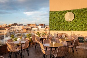 A rooftop patio with wicker furniture and a view of the cityscape.