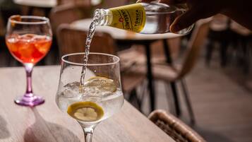Une main verse une boisson d’une bouteille dans un verre, dans lequel on a mis une tranche de citron.