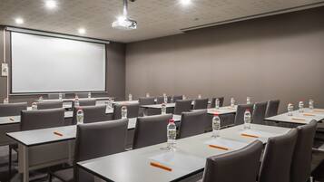 A conference room with tables, chairs, a projector screen, and water bottles.
