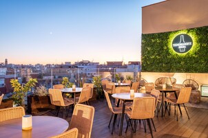 Un espacio al aire libre con mobiliario de mimbre y vistas a la ciudad.