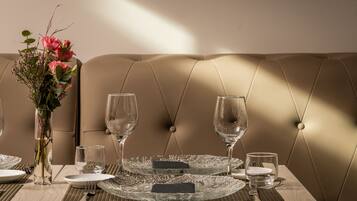 A dining table set with plates, cutlery, and glasses, with a vase of flowers on the left.