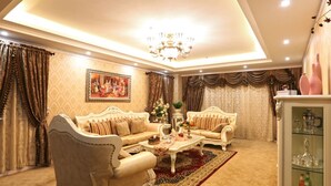 A luxurious living room with ornate furniture, a chandelier, and a decorative rug.