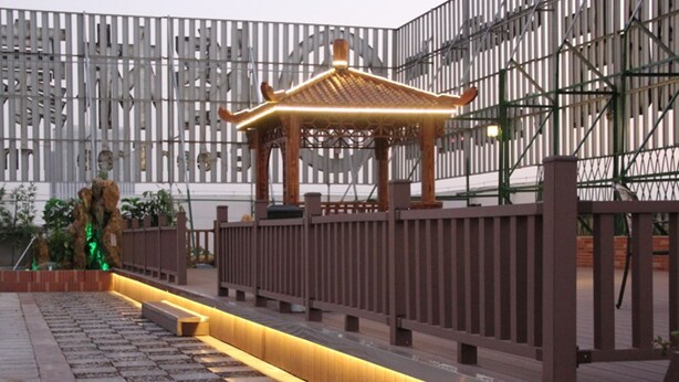 A courtyard with a traditional pavilion, stone pathway, and a modern fence.