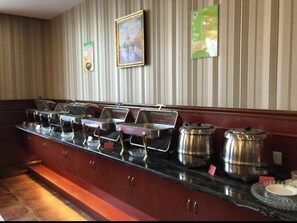 A buffet setup with multiple serving stations, a wooden counter, and a striped wall in the background. - GreenTree Inn BengBu NongJi Market ChangPing Street Hotel (Bengbu)