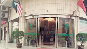 A building with a curved entrance, glass doors, and potted plants on either side. - GreenTree Inn Yancheng Xiangshui Bus Station Express Hotel (Yancheng)