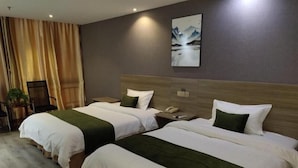 A hotel room with two beds, a nightstand, a chair, and a painting on the wall. - GreenTree Inn Yancheng Xiangshui Bus Station Express Hotel (Yancheng)