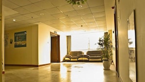 A spacious lobby with a tiled floor, a seating area with sofas, a large potted plant, and a wall-mounted sign. - GreenTree Inn Yancheng Xiangshui Bus Station Express Hotel (Yancheng)
