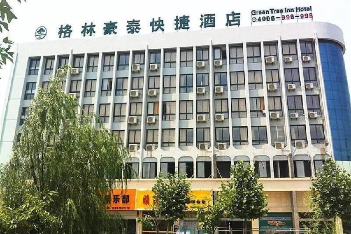 A hotel building with multiple floors, air conditioning units, and a signboard.