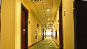 A long, narrow hotel corridor with doors on both sides, carpeted floor, and overhead lighting. - GreenTree Inn Yancheng Xiangshui Bus Station Express Hotel (Yancheng)