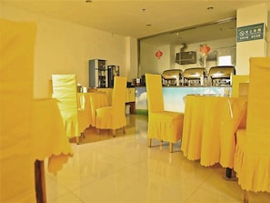 A restaurant with yellow tablecloths and chairs, a counter with food preparation equipment, and a no-smoking sign.