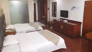 Quarto de hotel com duas camas, televisão, escrivaninha e guarda-roupa.