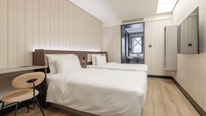Ein Hotelzimmer mit zwei Betten, einem Schreibtisch, einem Stuhl und einem Fernseher.