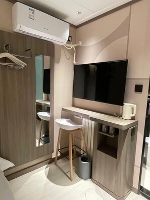 Un baño moderno con televisión integrada, un espejo, un lavabo e inodoro.