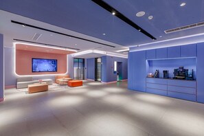 A modern hotel lobby with a seating area, a reception desk, and a large screen. - Hanting Hotel (Beijing)