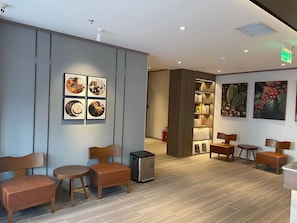 A modern interior with seating, a bookshelf, and framed pictures on the walls.