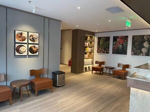 A modern hotel lobby with wooden furniture, a coffee machine, and a bookshelf. - Hanting Hotel (Beijing)