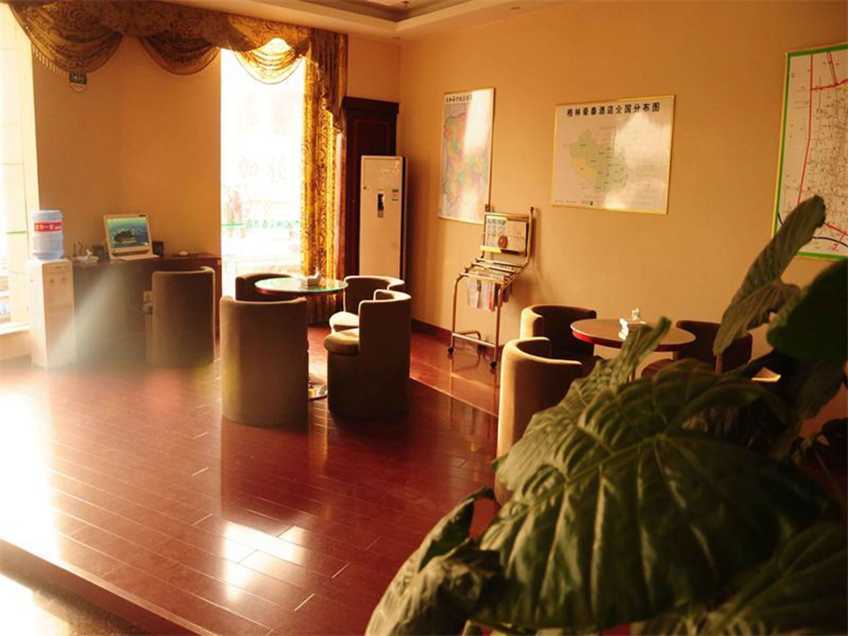 A hotel lobby with a reception desk, seating area, and a map on the wall.