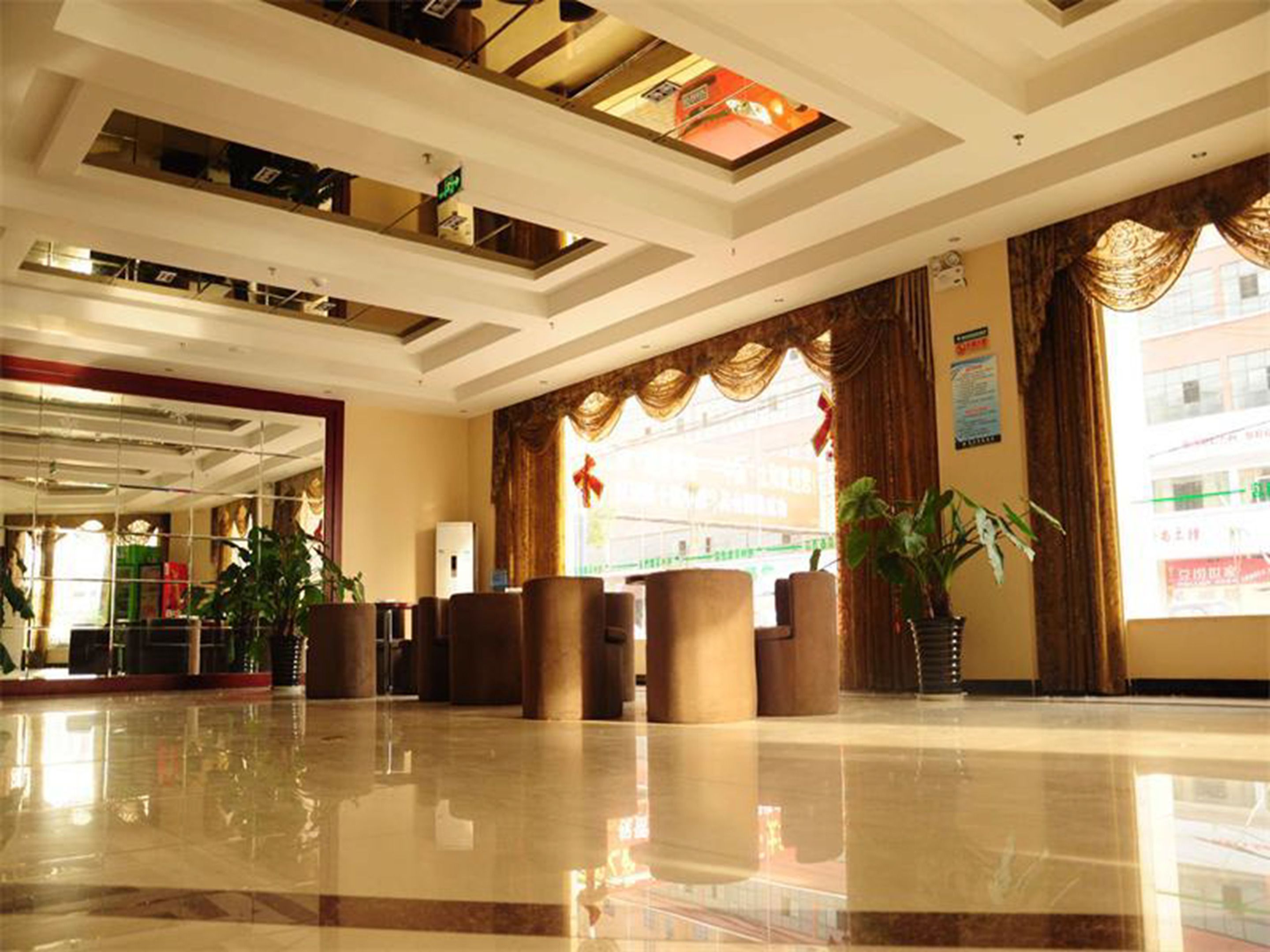 A spacious lobby with a polished marble floor, a reception desk, and a large window with curtains.