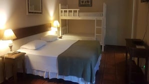 Una cama individual con cabecera, dos lámparas de noche, una cama litera encima, una mesita con un teclado y un cuadro en la pared.