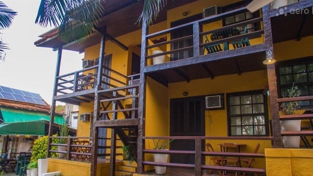 Un edificio amarillo con balcón, asientos al aire libre y una escalera.