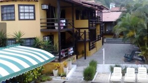 Un edificio amarillo con un balcón, una zona de estar al aire libre techada y una escalera que conduce al piso superior.