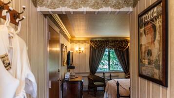 Une chambre d’hôtel avec un lit, une chaise, une commode et une fenêtre avec des rideaux.