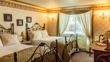 A bedroom with two beds, a desk, and a window with curtains.