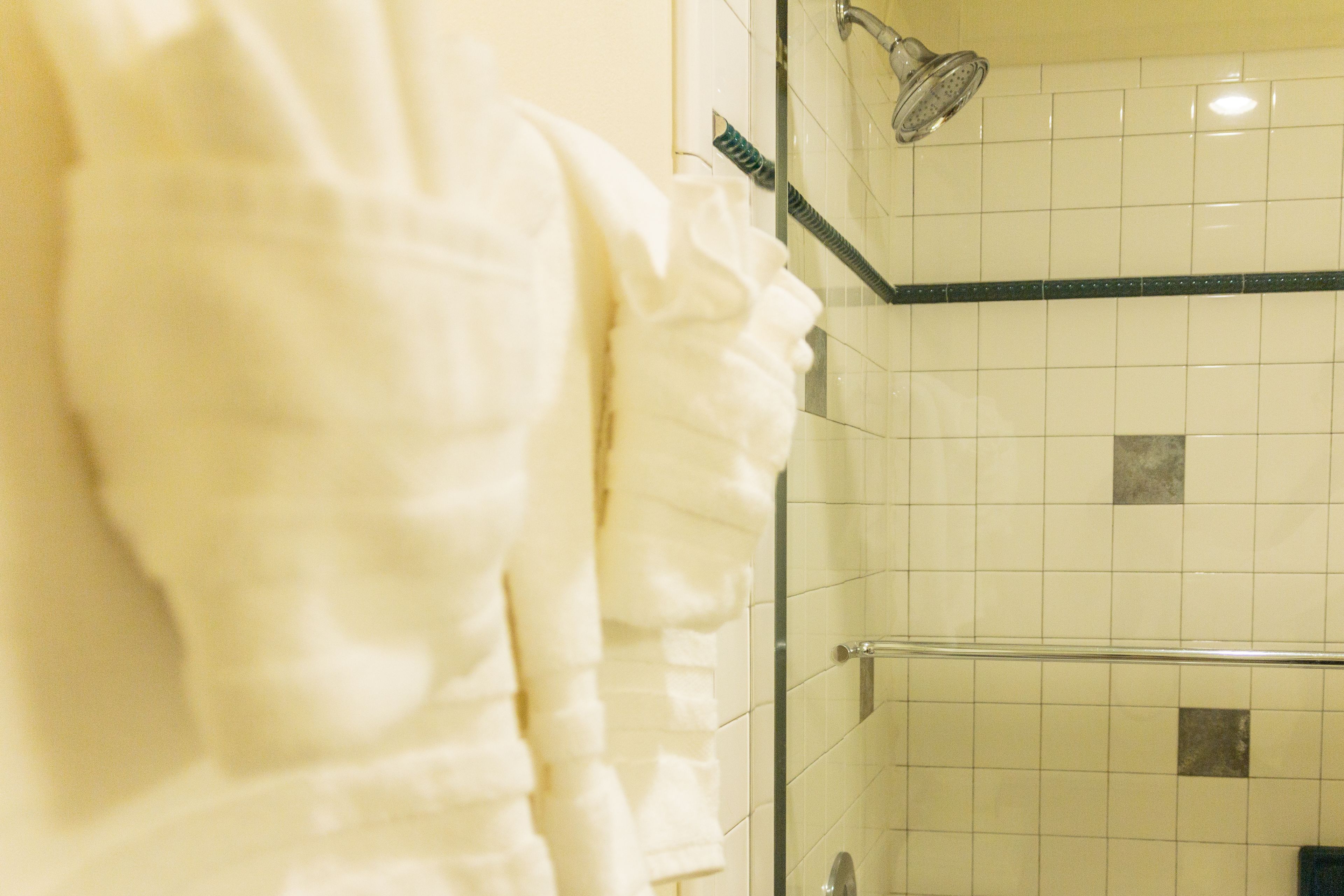 A bathroom with a glass shower enclosure, a towel rack, and a tiled wall.