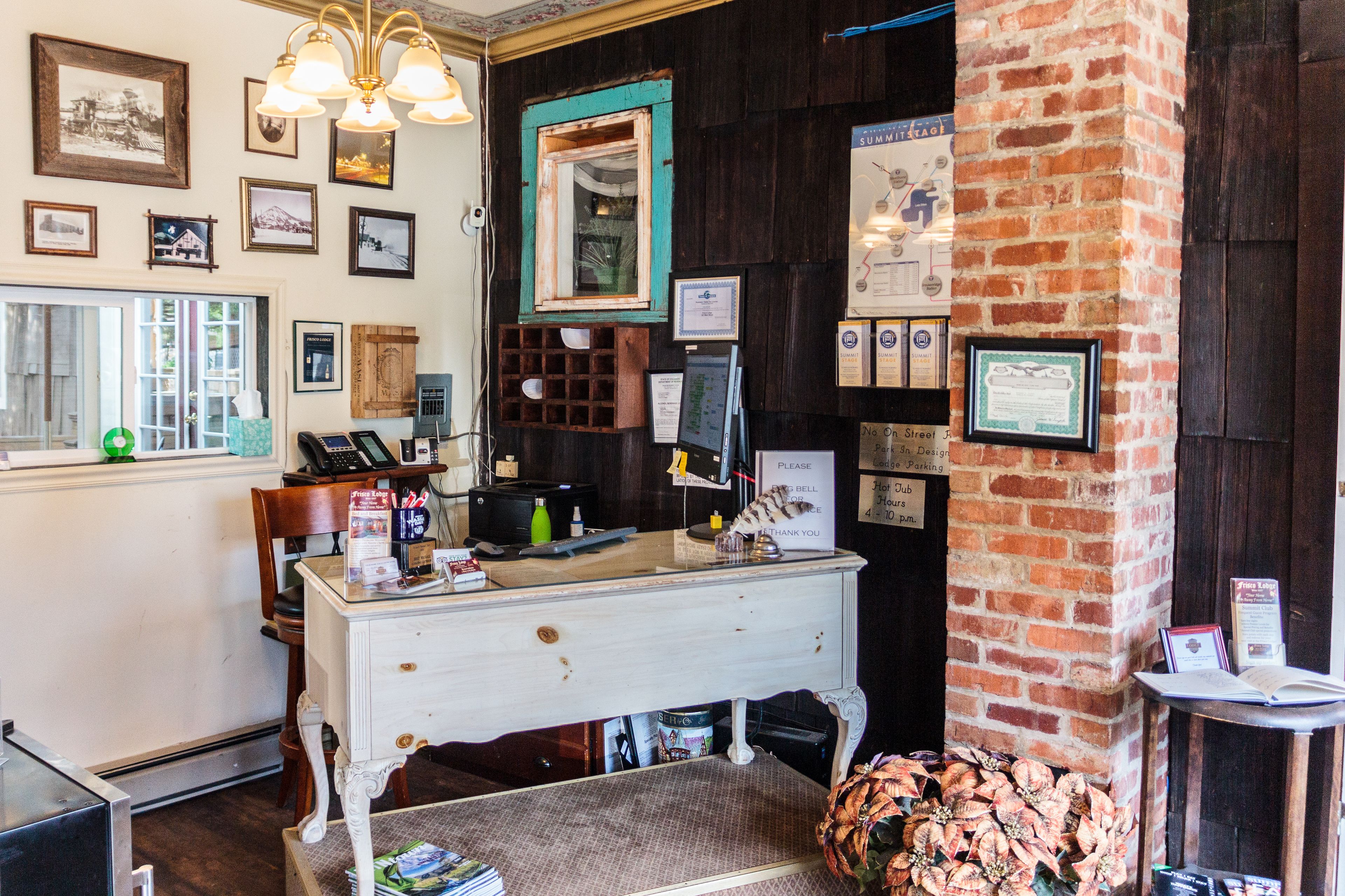 A vintage-style room with a wooden desk, a mirror, and various framed pictures on the walls.