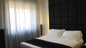 A hotel room with a large bed, a black headboard, and sheer curtains. - Hotel Pex (Rubano)