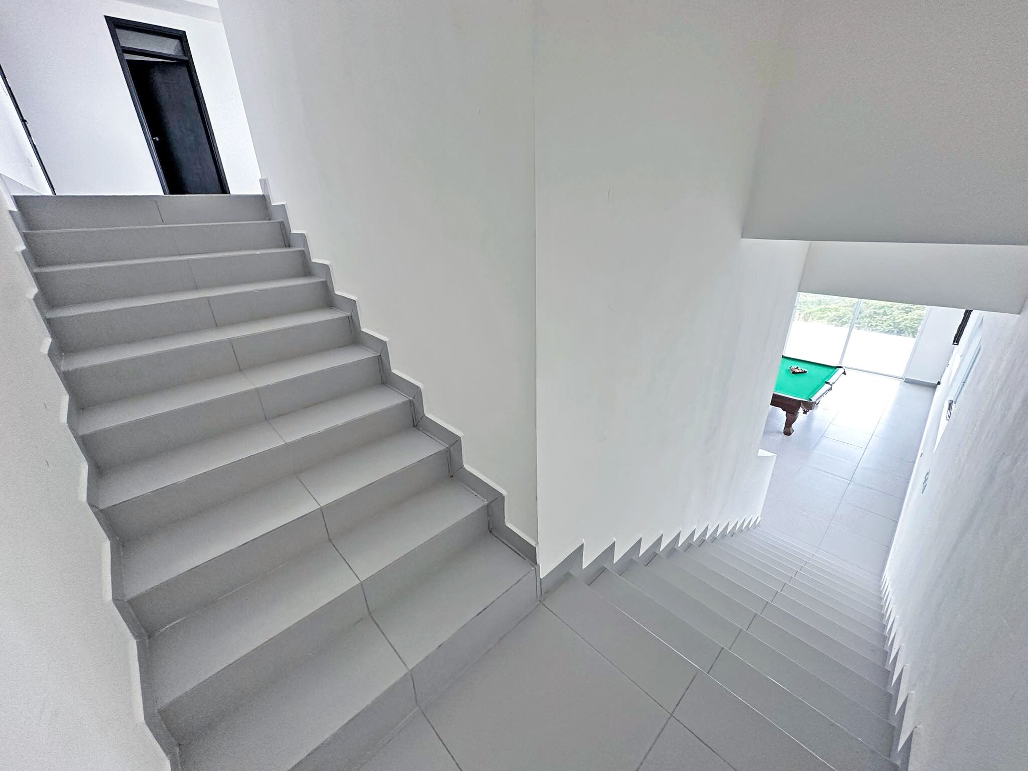 A staircase leading to a room with a pool table.
