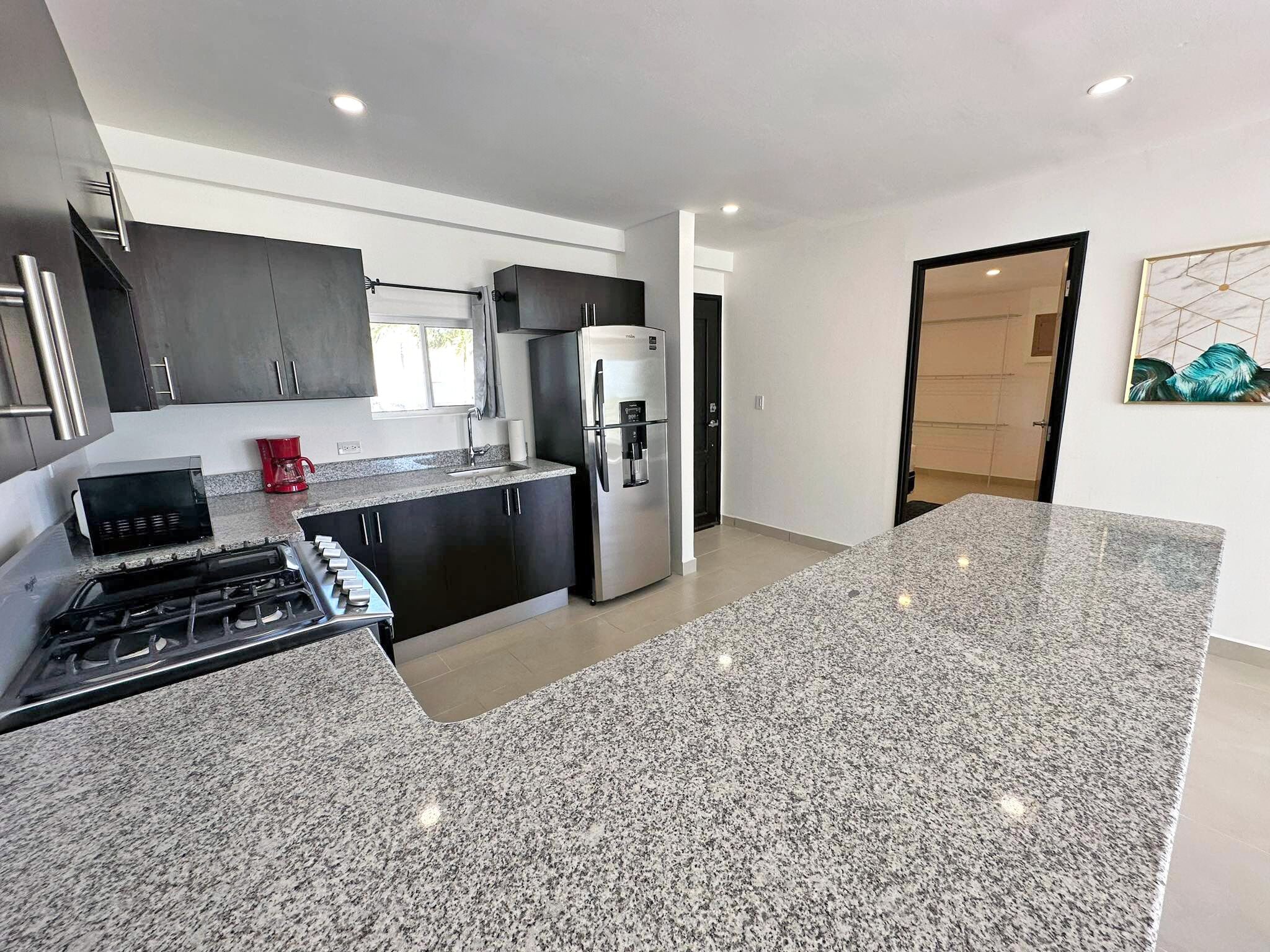 A modern kitchen with granite countertops, stainless steel appliances, and dark cabinetry.