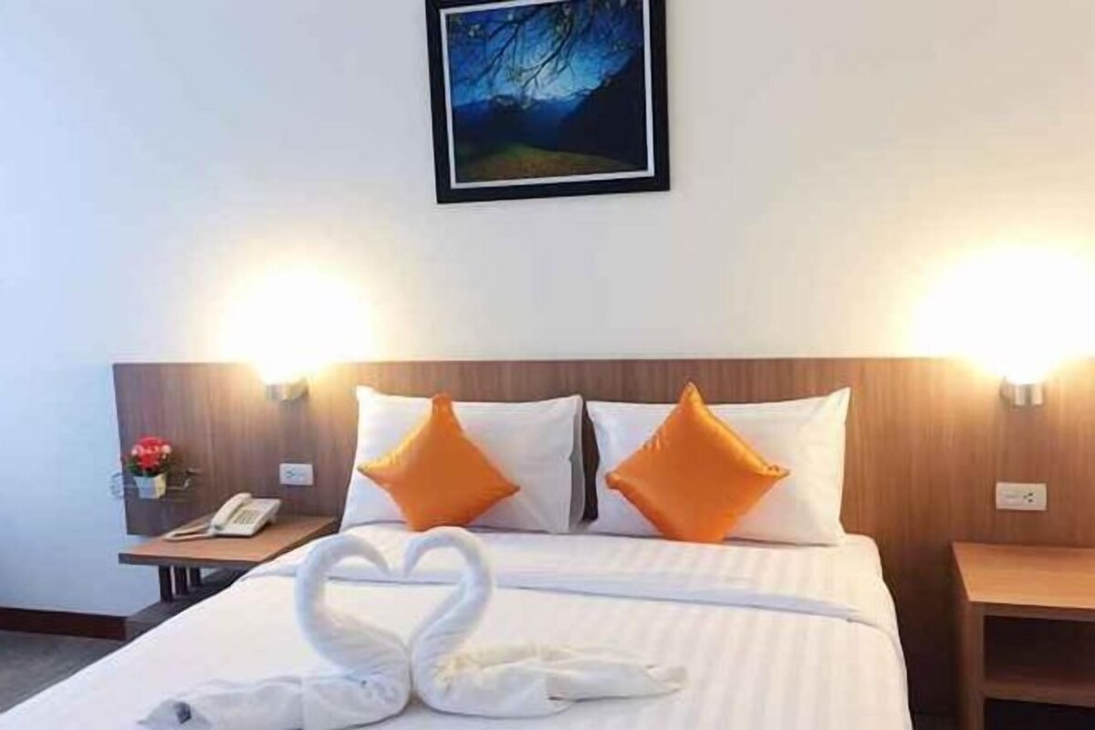 Habitación de hotel con cama, dos almohadas, mesita de noche, teléfono y lámpara de pared.