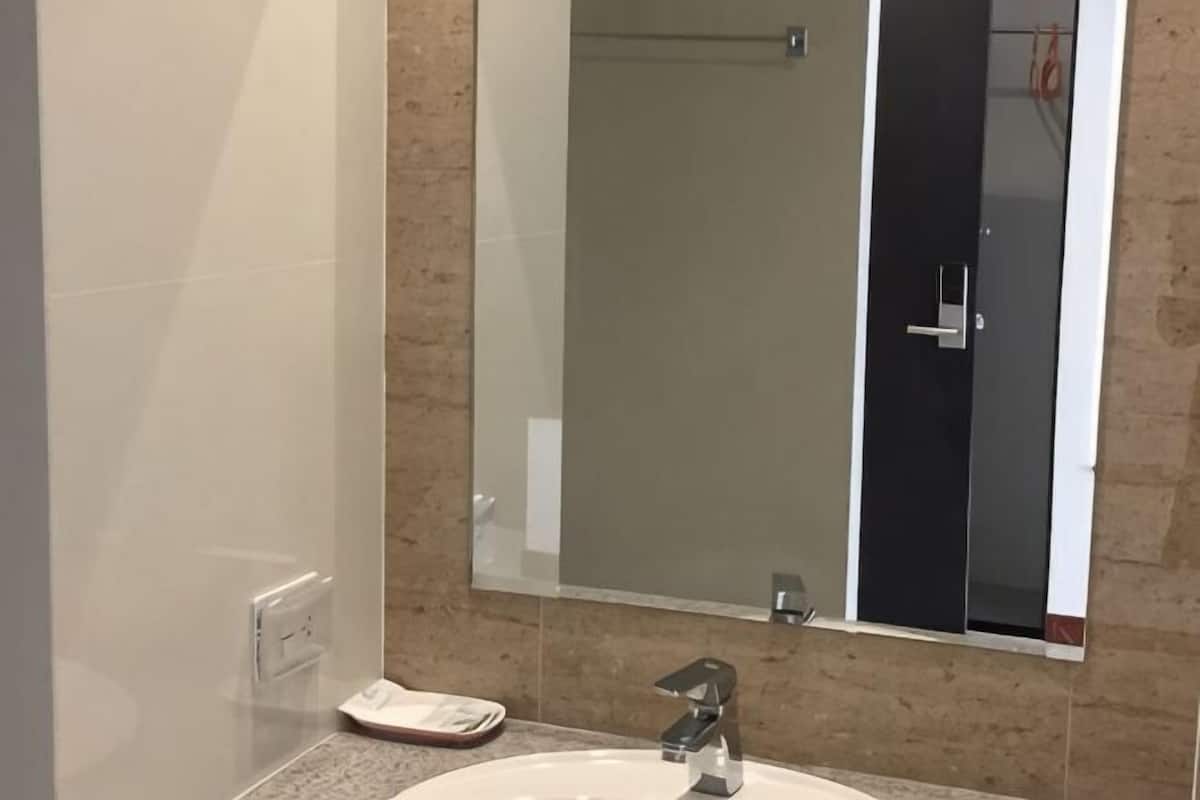 A bathroom with a white sink, a mirror, and a towel rack.