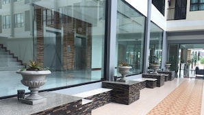 A modern lobby with a stone and wood accent wall, a tiled floor, and potted plants. - Orchid Riverview Hotel (Surat Thani)